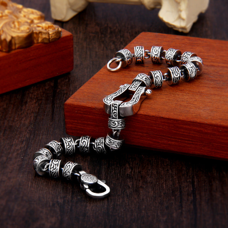 Silbernes Tang Dynastie Armband mit ornamentalen Perlen auf Holz.