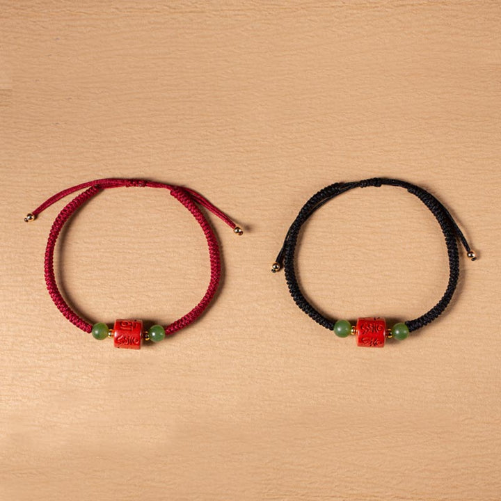 Zwei Armbänder mit roten Om Mani Padme Hum Perlen und grünen Steinen.