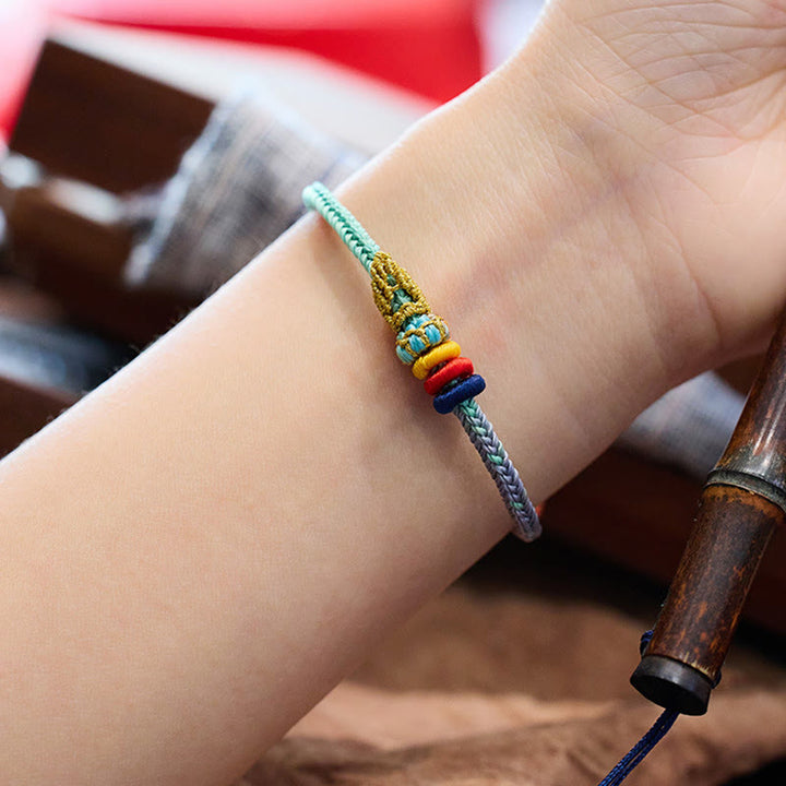 Gewebtes Armband mit Friedensknoten am Handgelenk getragen, bunte Perlen