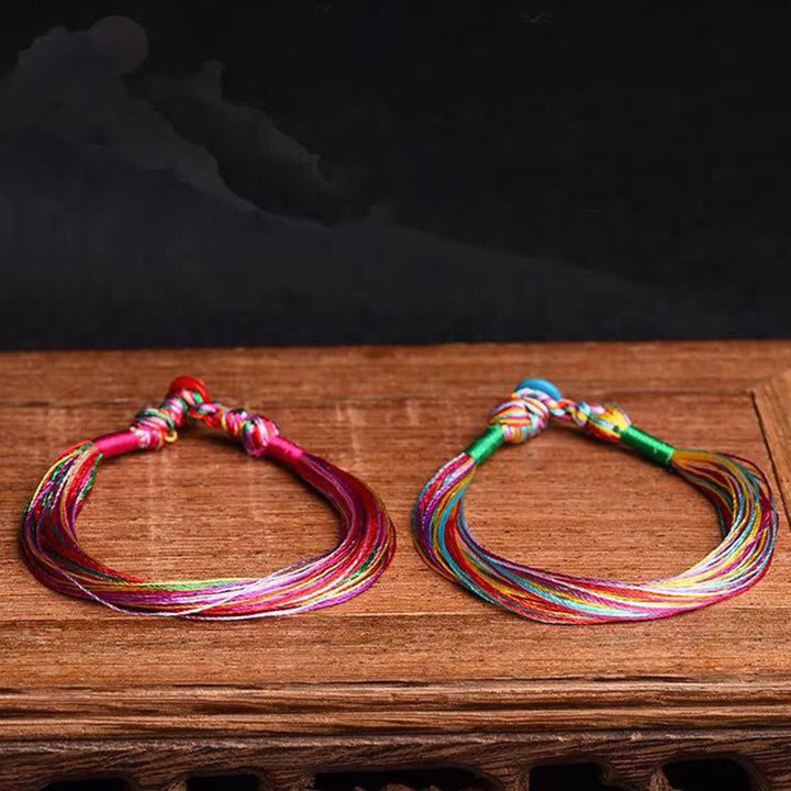 Zwei bunte Armbänder Fünffarben – Schutz Energie auf Holzoberfläche.