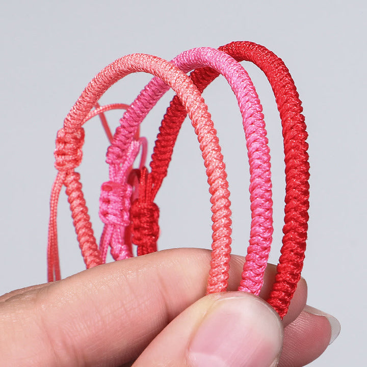 Tibetisches geflochtenes Armband mit Knoten in Rosa- und Rottönen, elastisch.