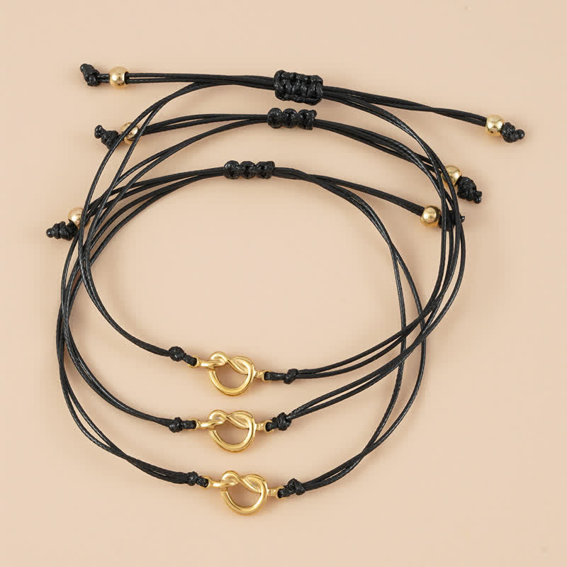 Drei schwarze Armbänder Freundschaft mit goldenen Ringen Knoten.