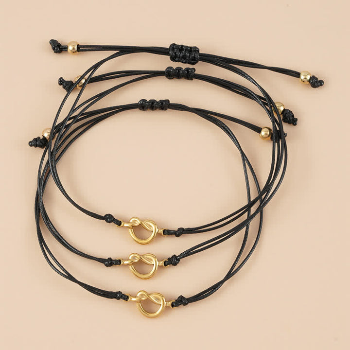Drei schwarze Armbänder Freundschaft mit goldenen Ringen Knoten.