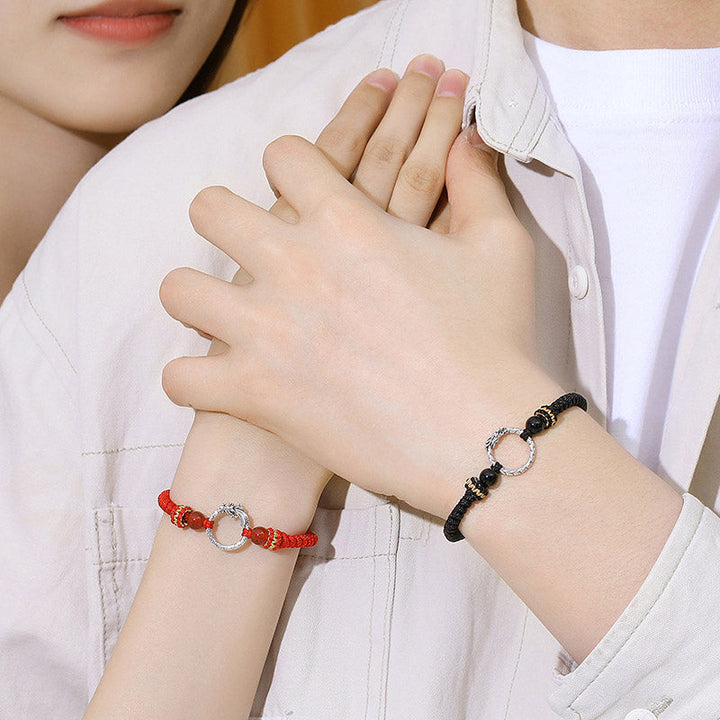 Rote und schwarze Armbänder mit Silberringen am Handgelenk getragen.