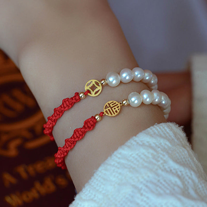 Armband Perle – Schutz & Glück mit roten Schnüren und Goldakzenten getragen