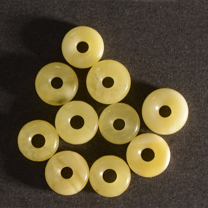 Zehn cremefarbene Jade Donut Perlen auf grauem Untergrund arrangiert.