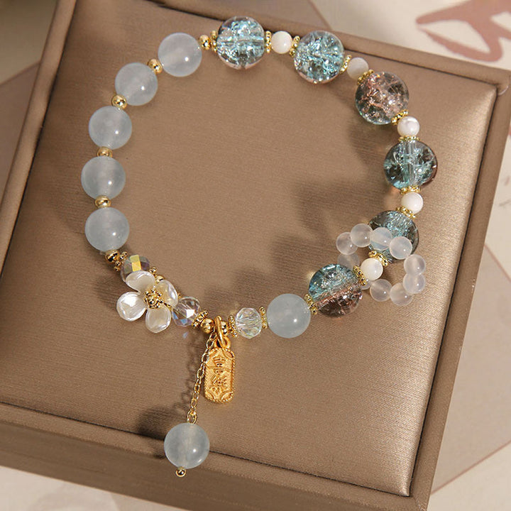 Elegantes Armband mit Mondstein und glitzernden Kristallperlen auf beiger Oberfläche.