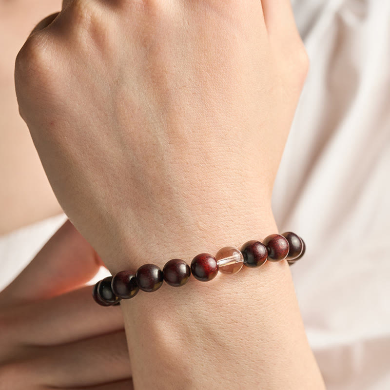 Armband mit dunkelroten Perlen und weißem Kristall am Handgelenk getragen