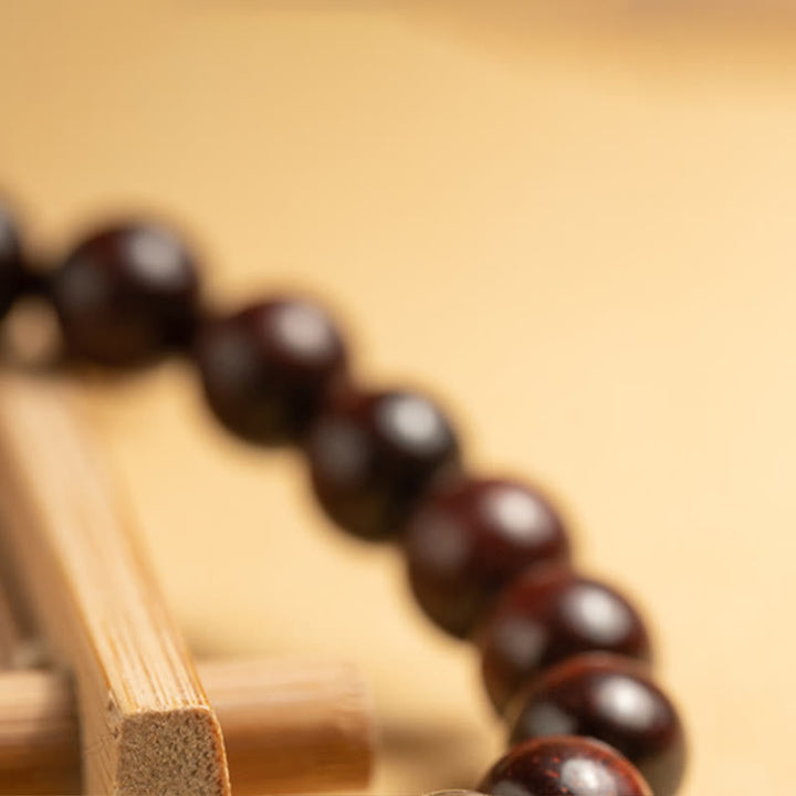 Armband mit dunklen Holzperlen und heller Sandelholzschnur elegant angeordnet.