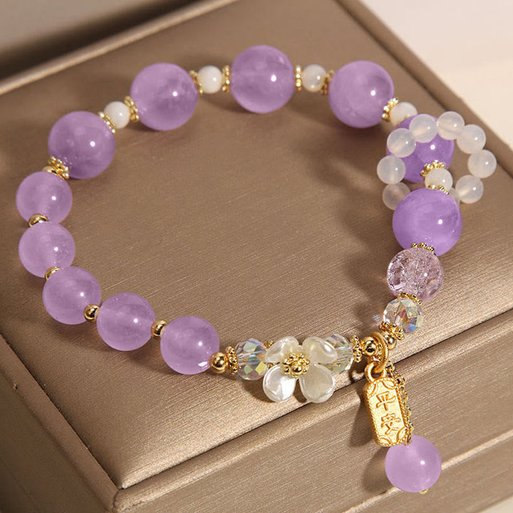 Armband Amethyst Kristall mit violetten Steinen auf beigem Hintergrund.