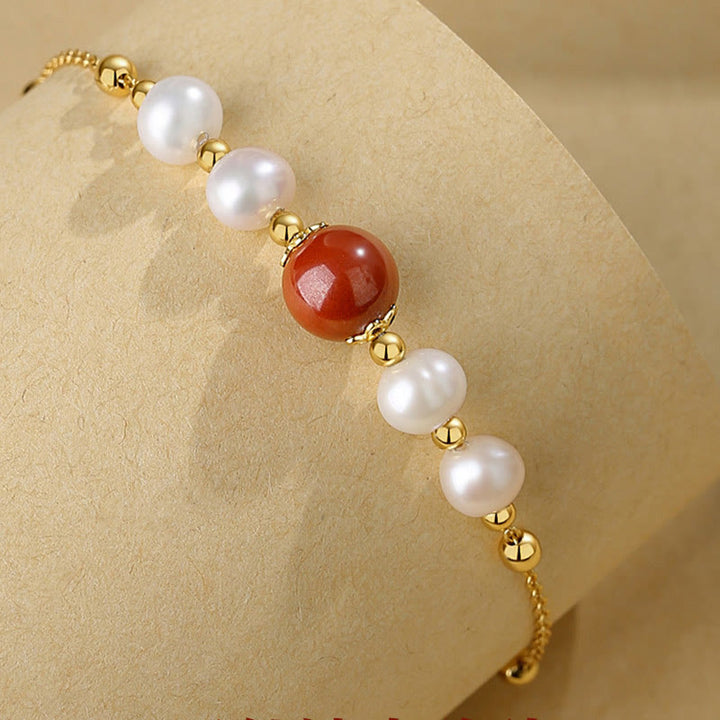 Elegantes Armband mit Perlen und rotem Zinnober Stein, gold verziert.
