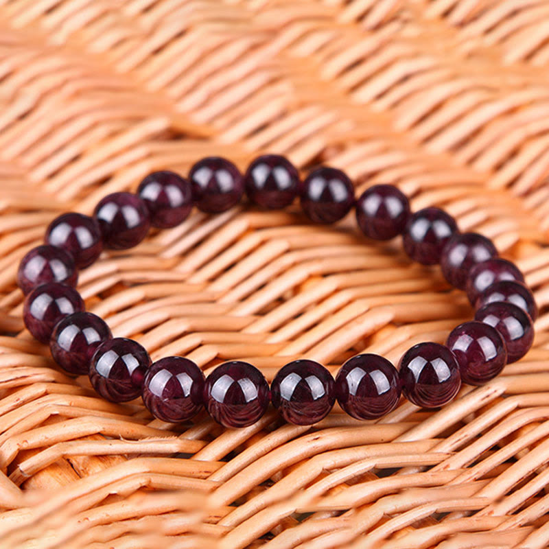 Armband Granat Perlen glänzend dunkelrot Naturstein elastisch Holzhintergrund