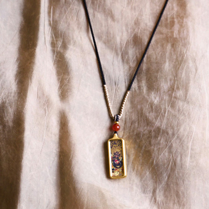 Schmuck Kette mit goldenem Anhänger rote Perle am Hals