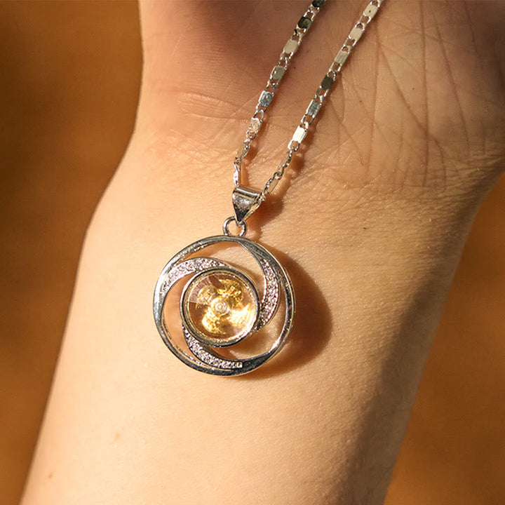 Silberne Spiralkette mit goldenem Kristall Anhänger an Hand getragen