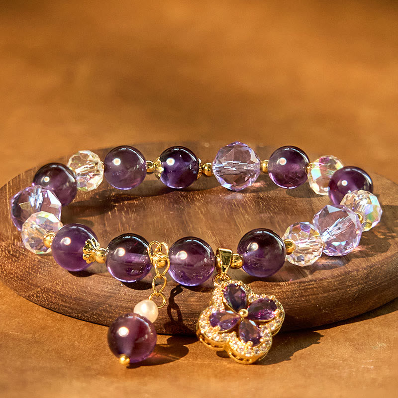 Amethyst Kristall Armband mit Kleeblatt Charm auf Holzoberfläche.