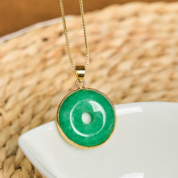 Grüne Jade Kette mit goldenem Anhänger auf weißer Keramik Naturstein