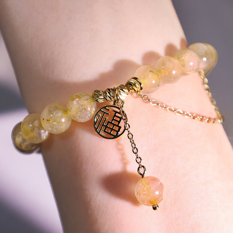 Citrin Armband mit Fu-Zeichen Anhänger am Handgelenk, goldfarben, elegant.
