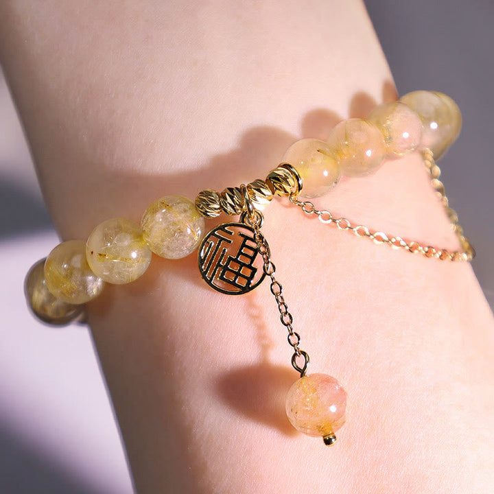 Citrin Armband mit Fu-Zeichen Anhänger am Handgelenk, goldfarben, elegant.