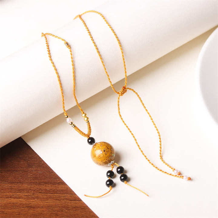 Goldfarbene Kette mit Ebenholz Perlmutt Buddha Anhänger Naturstein Balance