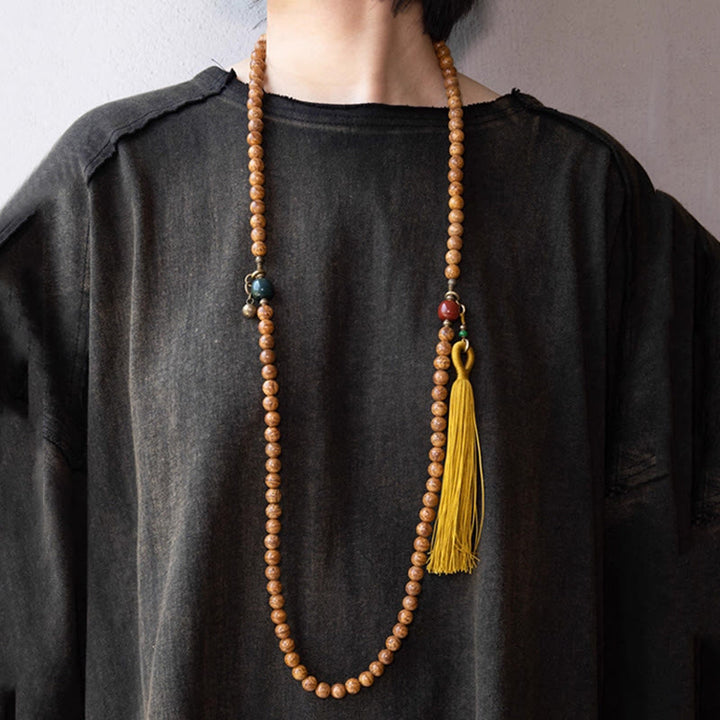Mala Bodhi Halskette aus Holzperlen mit gelbem Quastenstern auf schwarzem Shirt.