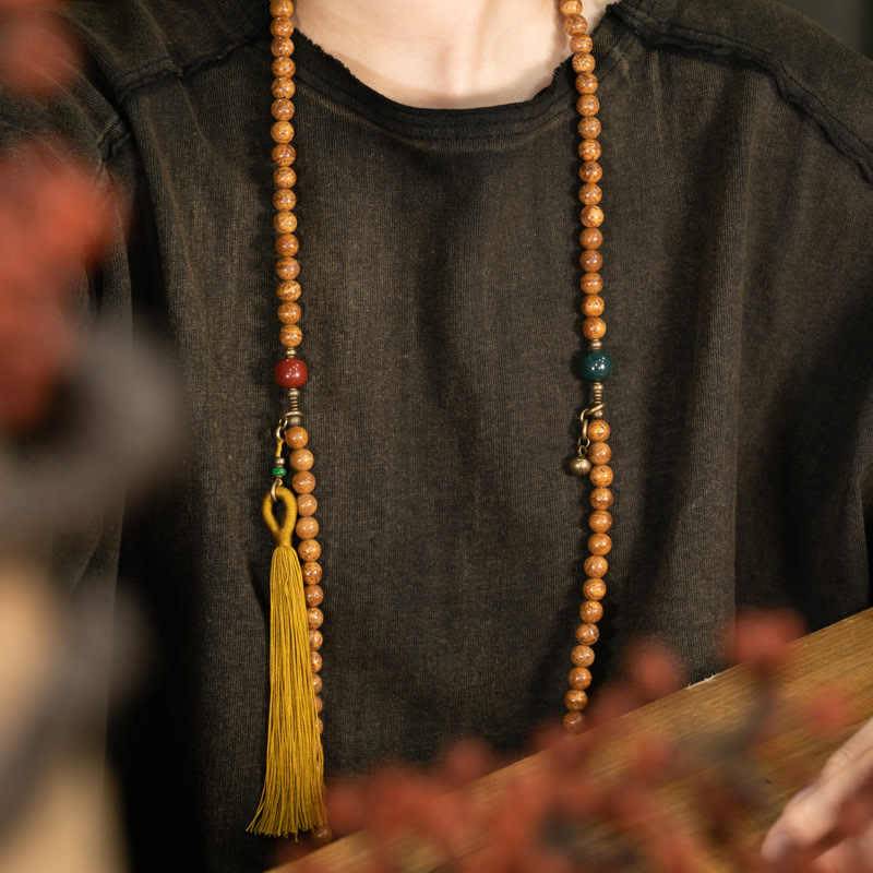 Mala Bodhi Halskette mit Holzperlen und goldener Quaste getragen.