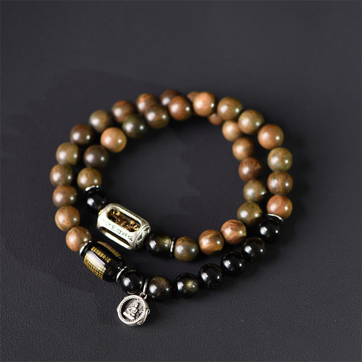 Armband Sandelholz Obsidian mit Metallverzierungen auf grauem Hintergrund