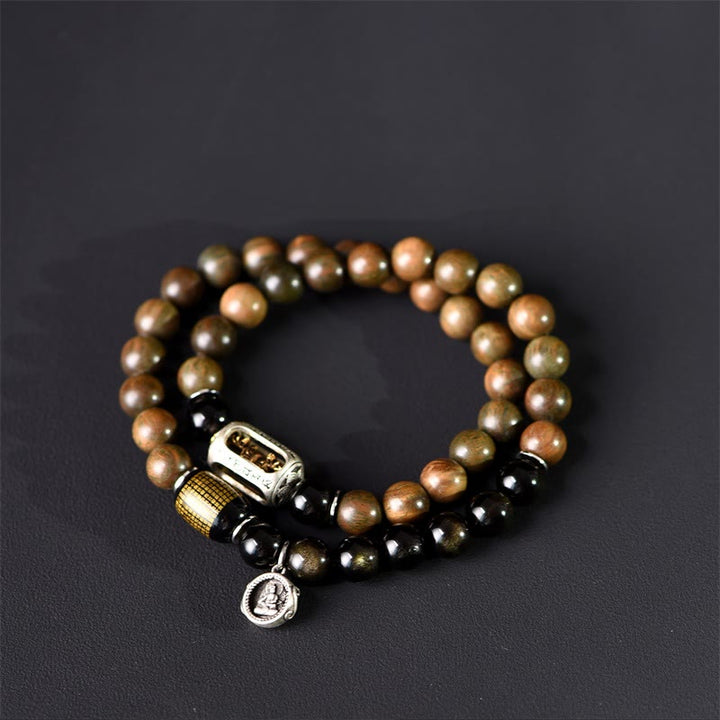 Armband Sandelholz Obsidian mit Metallverzierungen auf dunklem Hintergrund.