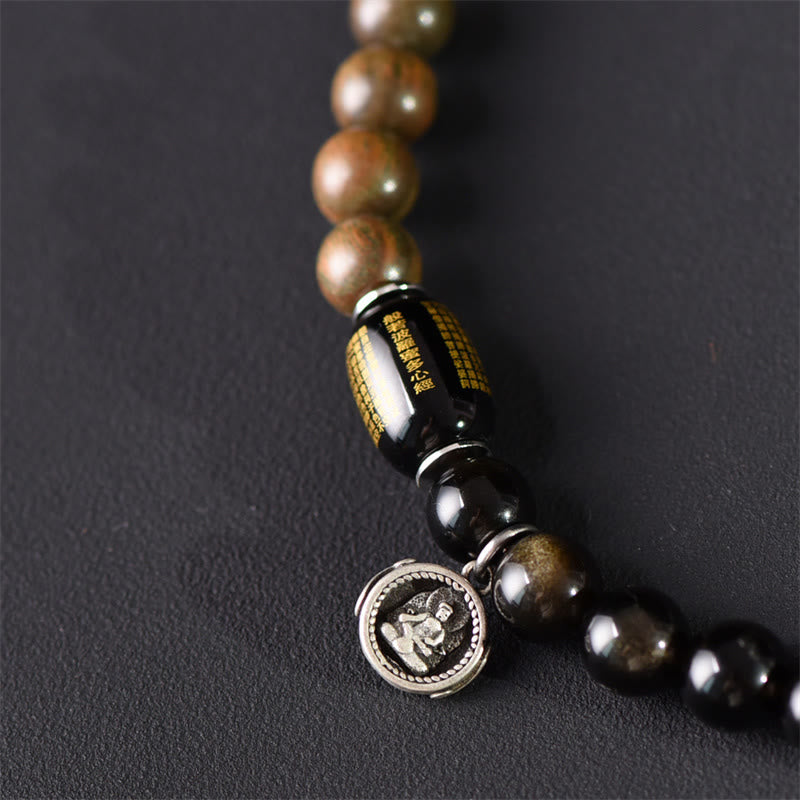 Armband Sandelholz Obsidian mit Silber Charm auf dunklem Hintergrund.