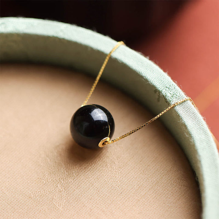 Schwarze Obsidian Kugelperle an 925er Silberkette mit goldenem Glanz