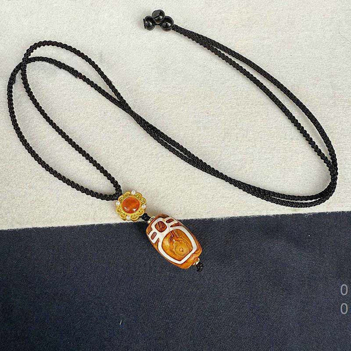 Schwarze Kette mit geschnittenen Bernstein Dzi-Anhänger Tibetagat Segen