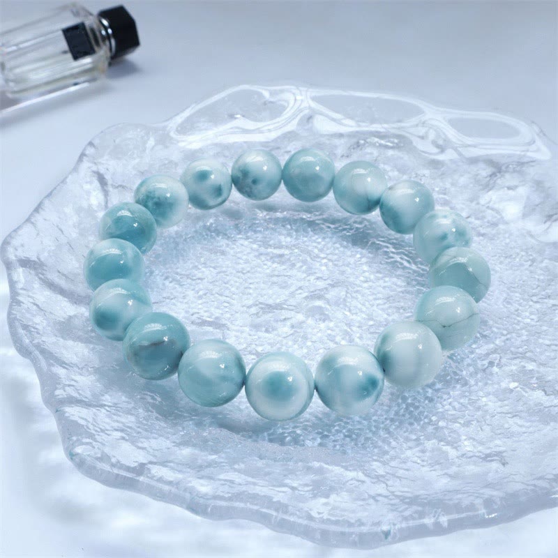 Larimar Armband mit hellblauen Perlen auf Eis Stein Untergrund.