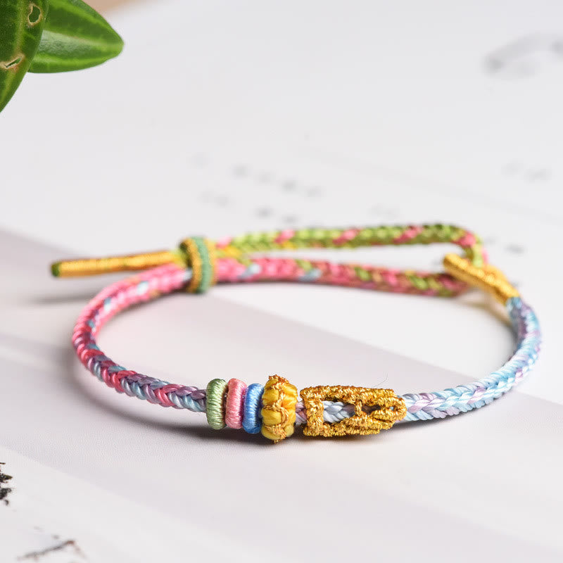 Buntes geflochtenes Armband mit Friedensknoten und goldener Schließe Flat Lay