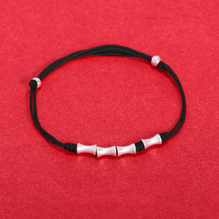 Schwarzes Armband 925 Silber Bambus mit elastischem Stoffband auf rotem Hintergrund.