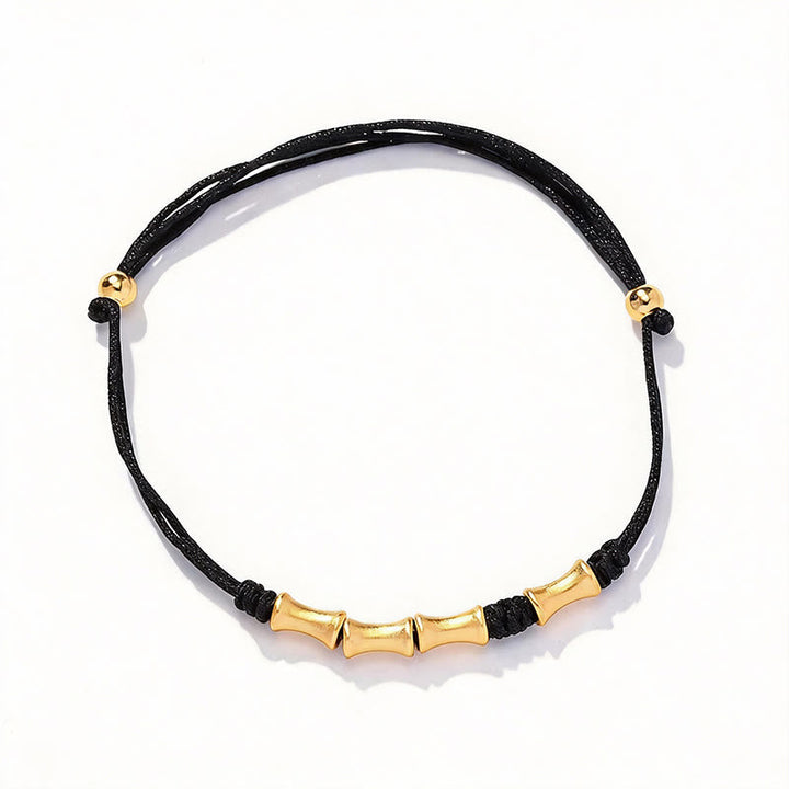 Schwarzes Armband mit goldenem Bambus-Design elegant präsentiert.