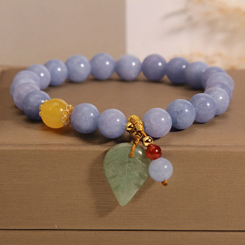 Armband Aquamarin Jade mit goldenem Schmuck auf Holztisch.