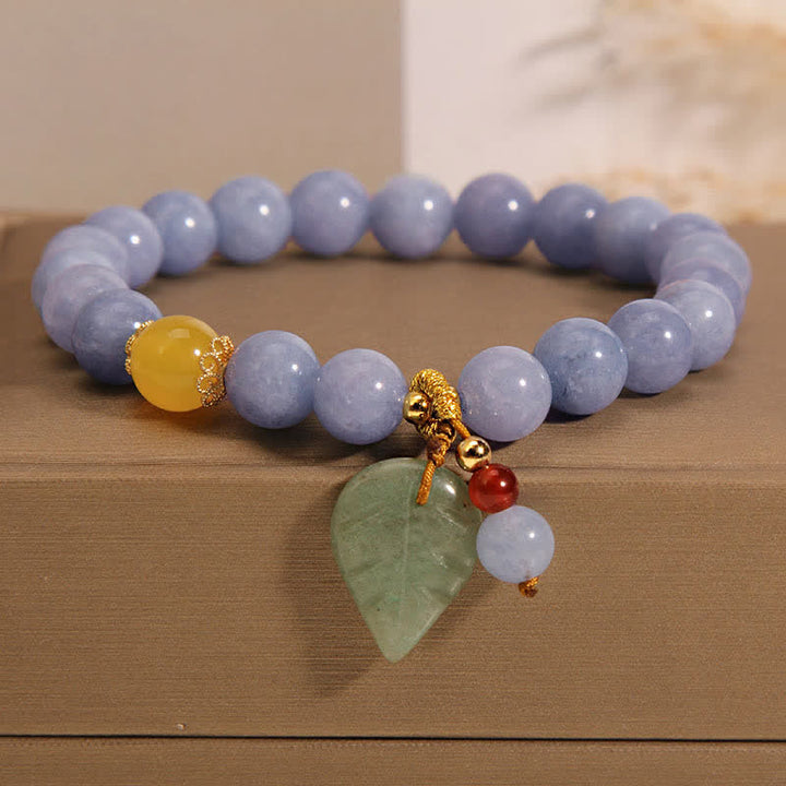 Armband Aquamarin Jade mit goldenem Schmuck auf Holztisch.