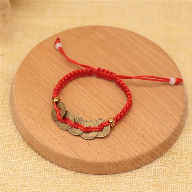 Rotes Armband Kupfer – Glück mit fünf Münzen Holzuntergrund.
