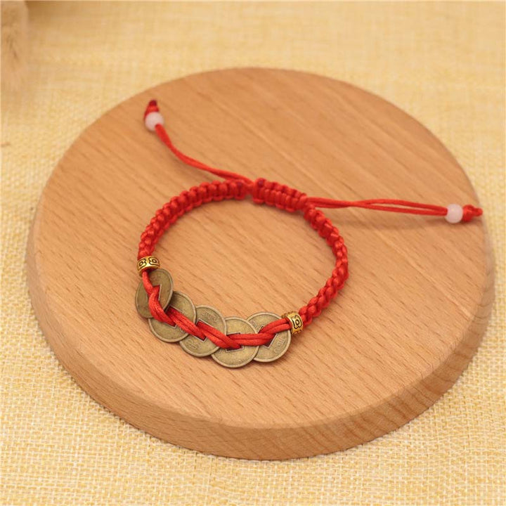 Rotes Armband Kupfer – Glück mit fünf Münzen Holzuntergrund.