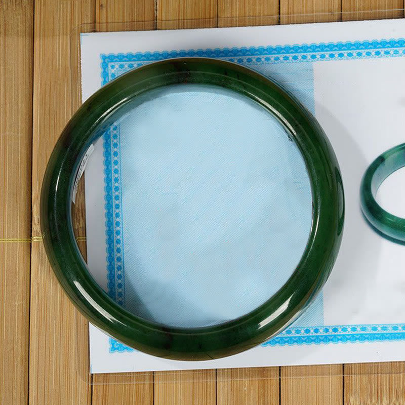 Grünes Jade Armband auf weißem Hintergrund mit blauem Dekor, Naturstein.