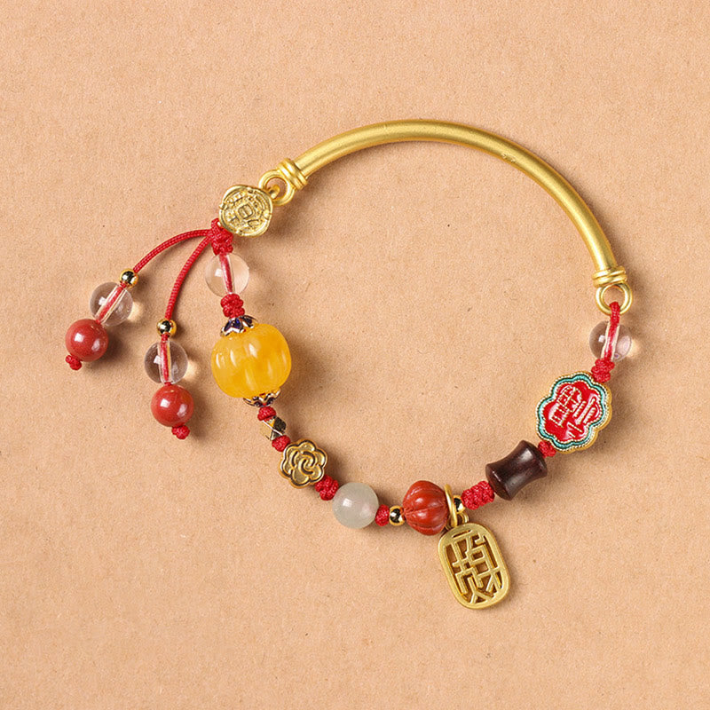 Armband Auspicious mit roten Perlen und goldenen Elementen elegant präsentiert.
