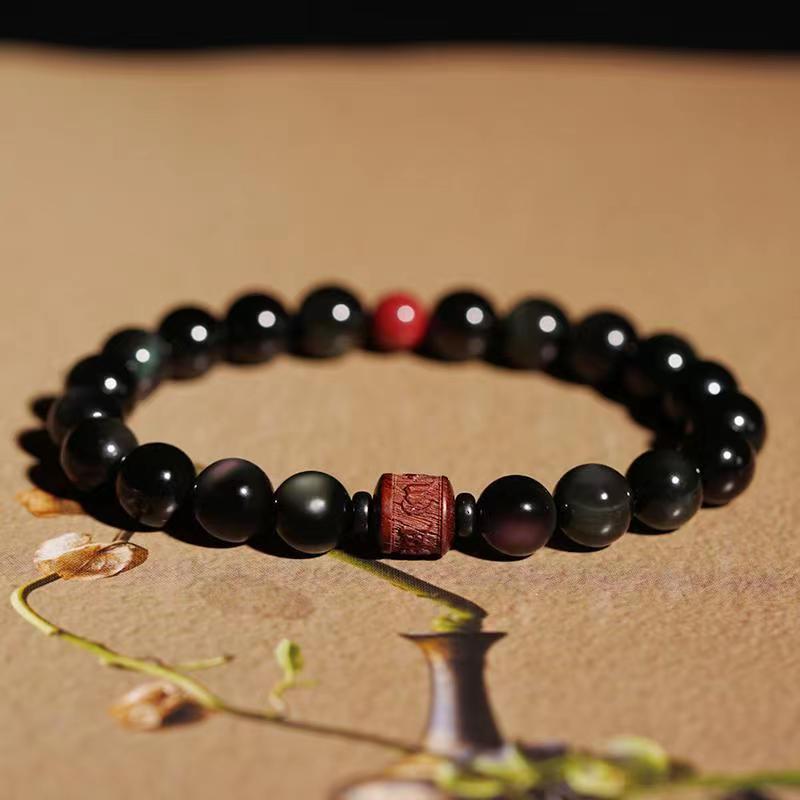 Schwarzes Obsidian Armband mit rotem Akzent auf Naturhintergrund elegant
