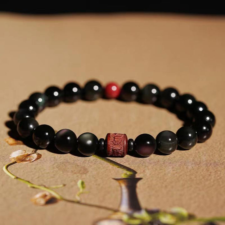 Schwarzes Obsidian Armband mit rotem Akzent auf Naturhintergrund elegant