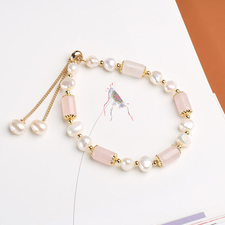 Elegantes Armband mit Perlen und rosa Kristallen, Golddetails.