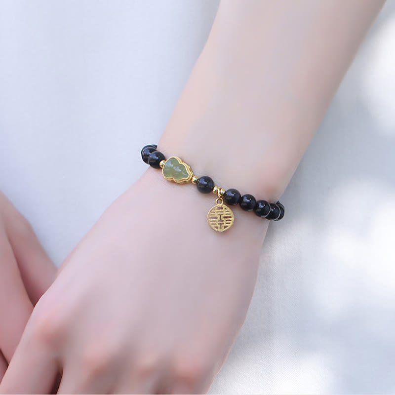 Armband Schwarzer Obsidian Jade mit goldener Verschlusskappe am Handgelenk getragen