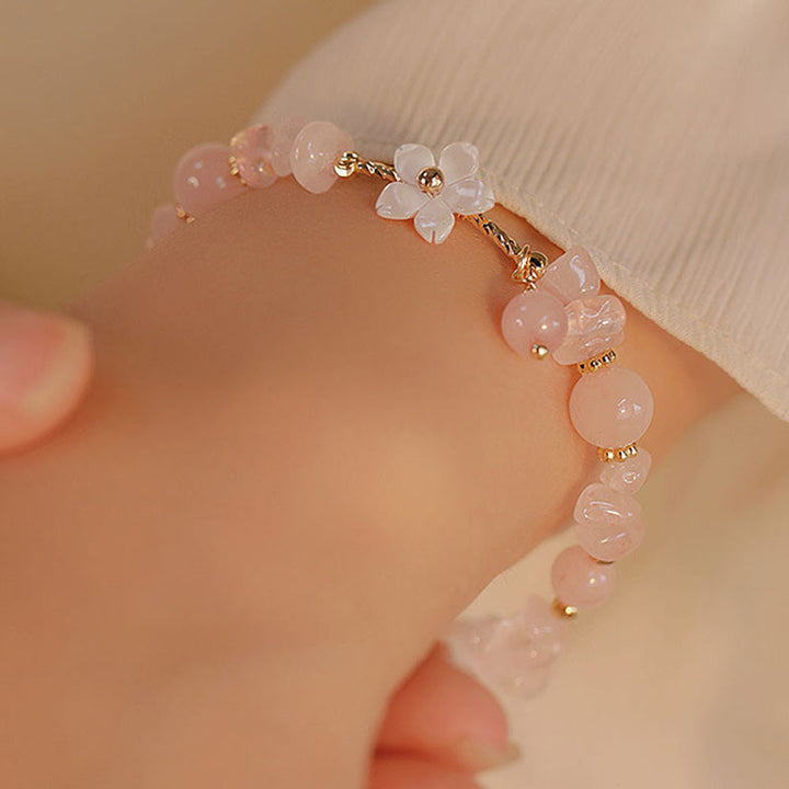 Rosenquarz Armband Kristall – Liebe am Handgelenk mit Blütendetail getragen
