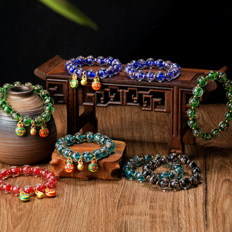 Bunte Armbänder mit Perlen und goldenen Anhängern auf Holz ausgestellt.