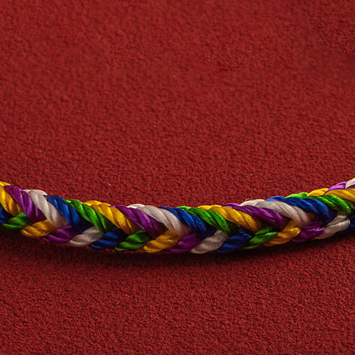 Buntes geflochtenes Armband auf rotem Hintergrund Glück Energie.