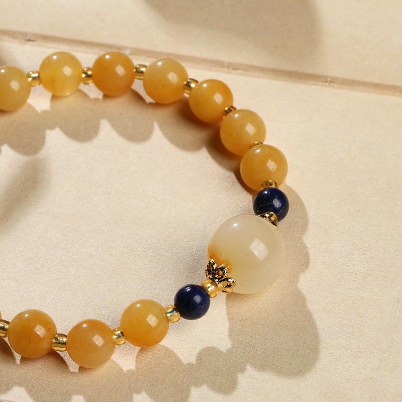 Gelbes Jade Armband mit Gold und dunklen Perlen elegant getragen