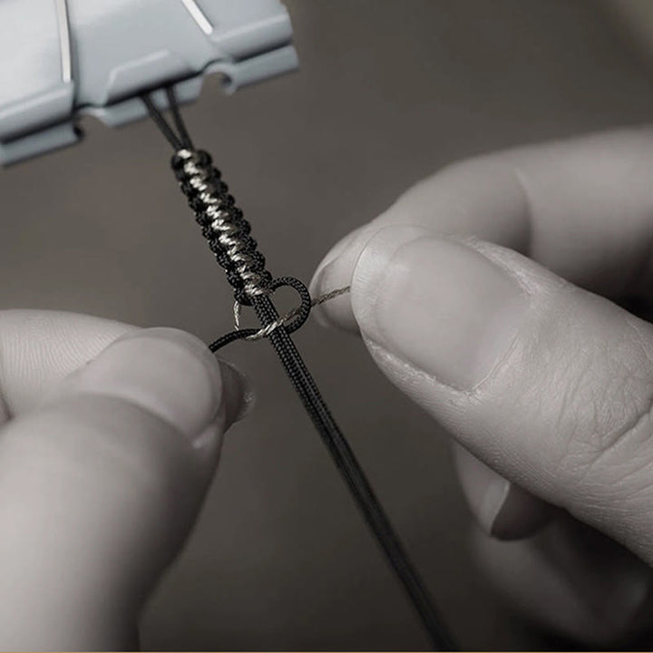 Schwarzes Armband mit Knoten wird von Händen gehalten präsentiert