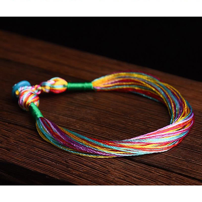 Farbiges Fünffarben Armband Schutz Energie bunte Fäden Holzoberfläche.